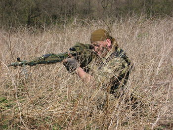 Sniped aiming with rifle at grassy field