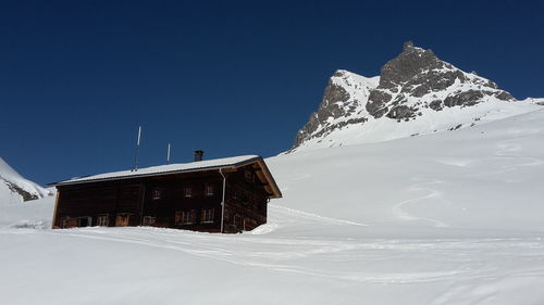 Built structure on snowcapped mountain against clear sky