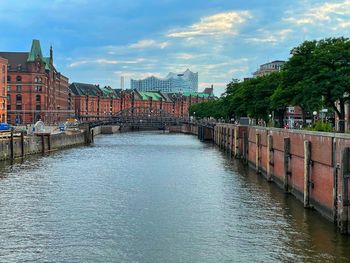 Bridge over river amidst buildings in city against sky