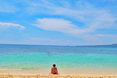 Rear view of woman sitting on beach