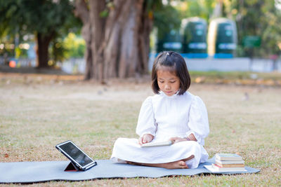 Girl sitting on book in park