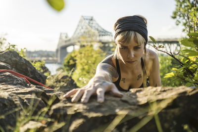 Tattooed girl rock climbing with friend reaching the top