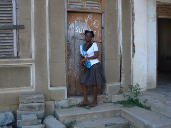 Portrait of young woman standing against brick wall