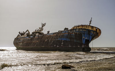 Abandoned boat in sea against clear sky