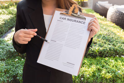 Midsection of woman holding paper with text