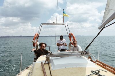 Friends in ship on sea against cloudy sky