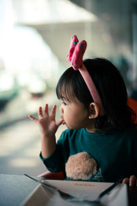 Baby girl sitting at table in restaurant