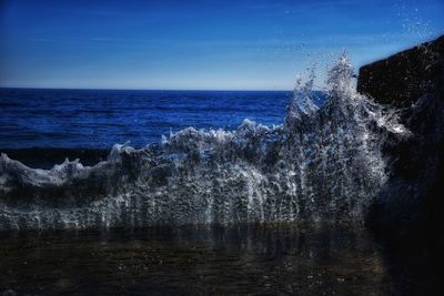 Sea waves splashing against clear sky