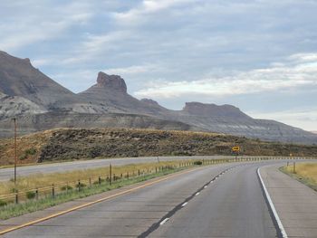 Road leading towards mountains against sky