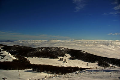 Scenic view of snowcapped mountains against blue sky