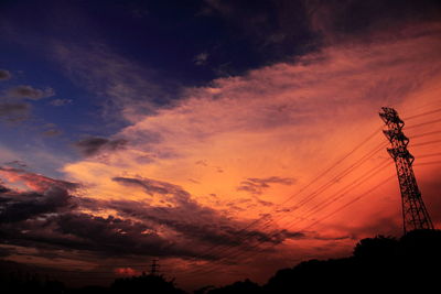 Low angle view of electricity pylon against cloudy sky