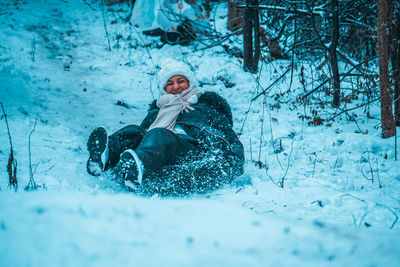 Cheerful woman sledding on snowy hill