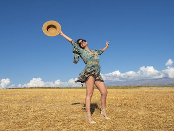 Woman in the field throwing hat to the sky