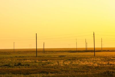 Electricity pylon on field against sky during sunset