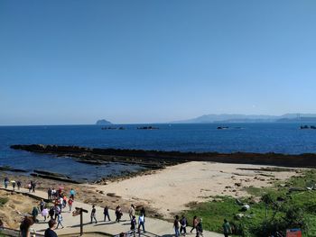 People on beach against clear sky