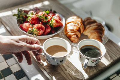 Midsection of man holding coffee cup on table