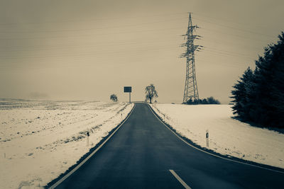 Road amidst trees against sky during winter