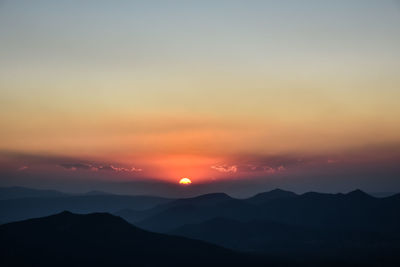 Scenic view of silhouette mountains against romantic sky at sunset