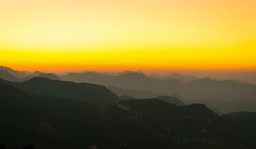 Scenic view of silhouette mountains against orange sky