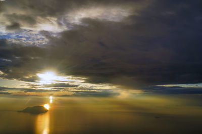 Sun streaming through clouds in sky during sunset