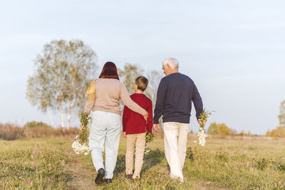 Senior couple walking with grandson on field