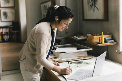 Side view of young woman working at home