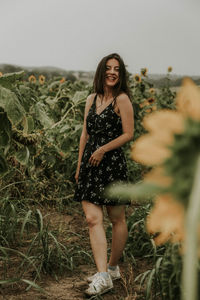 Young woman standing amidst sunflowers on field