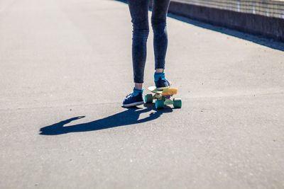 Low section of woman skateboarding on road