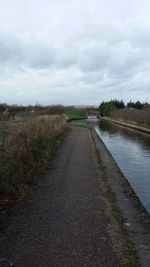 Road passing through landscape against cloudy sky