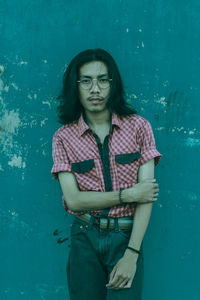 Portrait of young man standing against blue wall