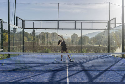 Young woman practicing stretching exercise on sports court