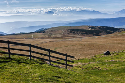Wooden fence in the mountain pasture on the cloudy sky background