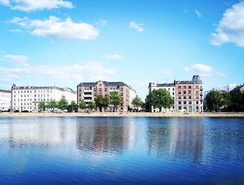 Buildings at waterfront against cloudy sky