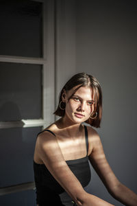 Portrait of young woman sitting against window