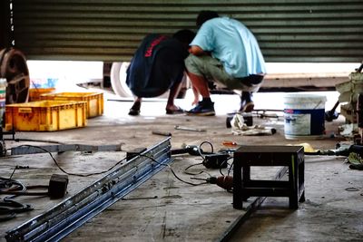 Rear view of mechanics working in repair shop