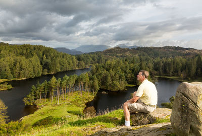 Full length of senior man sitting on rock