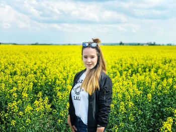 Portrait of smiling young woman with yellow flowers in field