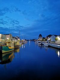 Sailboats moored at harbor against sky at dusk