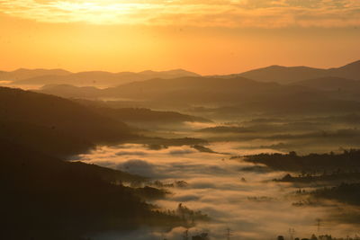 Scenic view of silhouette mountains against orange sky