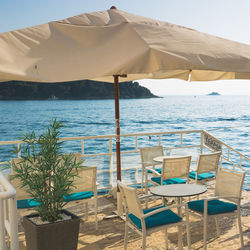 Chairs and table at beach against sky