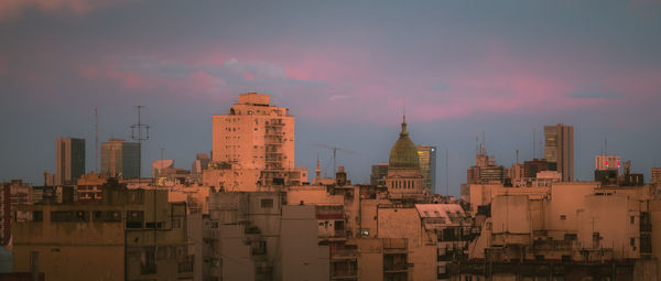 Buildings in city against cloudy sky