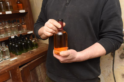 Midsection of man holding beer bottle