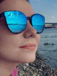 Close-up of young woman wearing sunglasses at beach