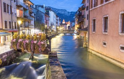 Canal amidst buildings in city against sky