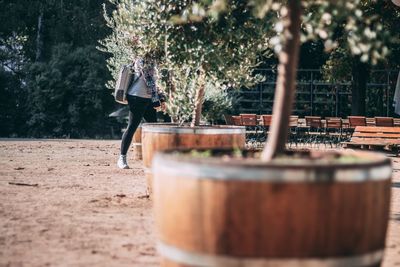 Side view of woman walking amidst potted plants at park