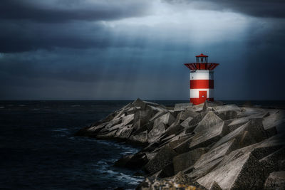 Lighthouse by sea against sky