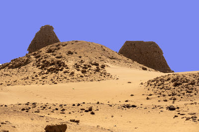 A pyramid destroyed beyond recognition in the foreground, in the desert of sudan.
