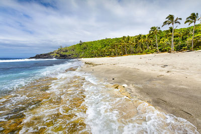 Sunny day with rocks, waves and sand at grande anse beach, reunion island