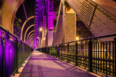 Illuminated bridge amidst buildings in city at night