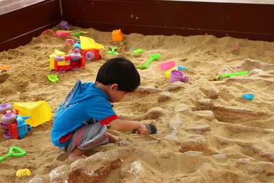 Side view of boy playing with toys on sand